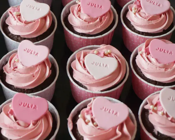 Rosa cupcakes med hjärtformade dekorationer med texten "JULIA". Perfekt för en speciell Julia!