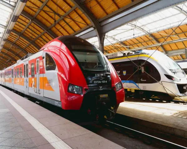 Dwa nowoczesne pociągi, czerwony i srebrny, czekają na pasażerów na dworcu. To idealny pociąg do poznania nowych miejsc.