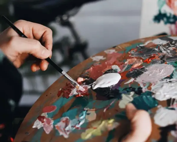 Une main mélange des couleurs vives sur une palette, prête à passer pour un peintre.