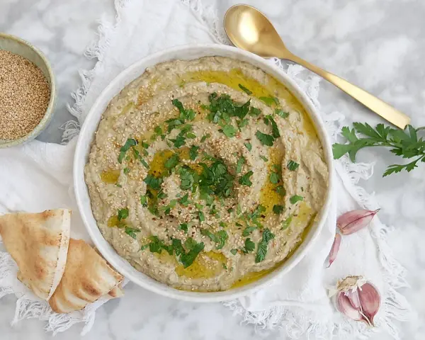 Crema de berenjena asada con aceite de oliva, perejil y semillas de sésamo, servida con pan de pita.
