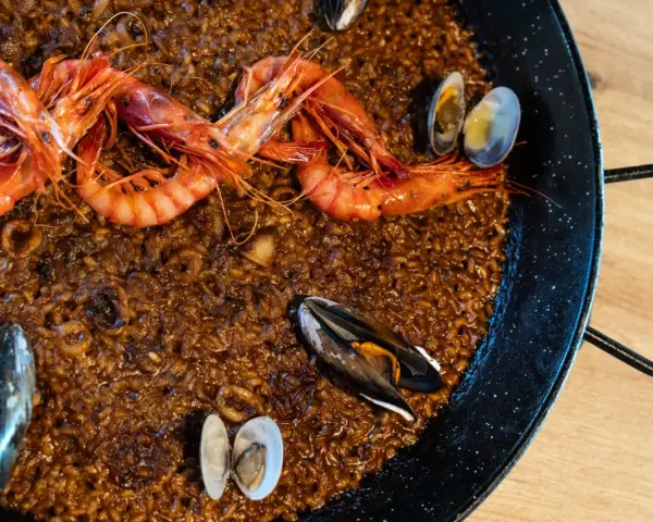 Paella de marisco con gambas rojas, mejillones y almejas sobre arroz dorado.