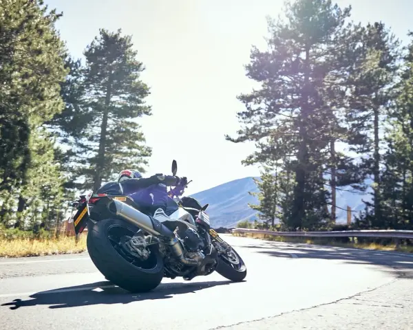 Motocyklista na zakręcie, otoczony lasem, z dumą prezentuje opony Pirelli. Jazda w stylu Pirelli klub.