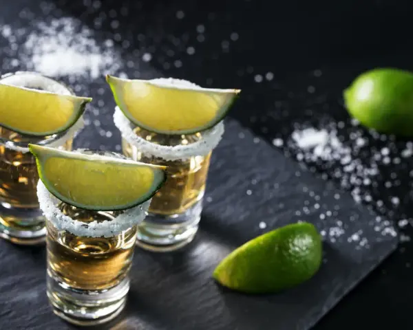 Szklanki z tequilą, ozdobione solą i ćwiartkami limonki. Idealne do picia z limonką, gdy zastanawiasz się, z czym pić tequilę.