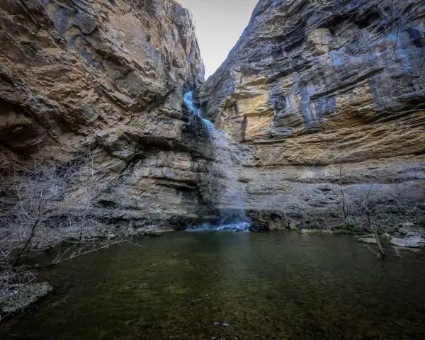 La cascada del Gollorio cae entre imponentes paredes rocosas, formando un estanque sereno.
