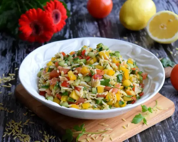 Kolorowa sałatka z makaronem orzo, pomidorami, ogórkiem i papryką. Idealna na letni obiad.