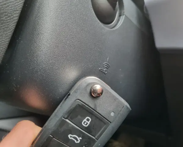 Kluczyk samochodowy z funkcją keyless go w pobliżu przycisku start.