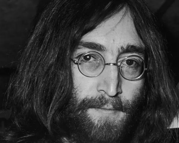 Nahaufnahme von John Lennon III. mit runden Brillengläsern und Bart.