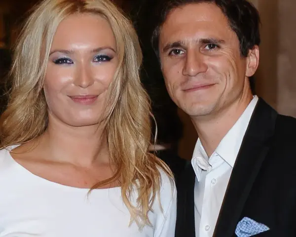 Uśmiechnięta para, być może rodzice Sambora Czarnoty, pozuje do zdjęcia. Kobieta ma blond włosy i białą sukienkę, mężczyzna czarny garnitur.