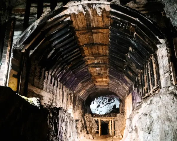 Wnętrze kopalni, drewniane wsporniki tworzą tunel, który prowadzi do jasnego otworu. To część kompleksu Rize.