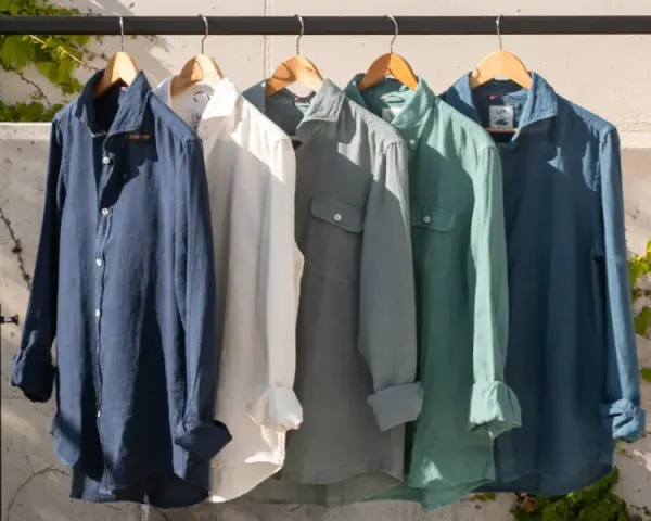 Cinco camisas de lino de colores cuelgan en una percha. El lino, de donde viene el lino, es una fibra natural.