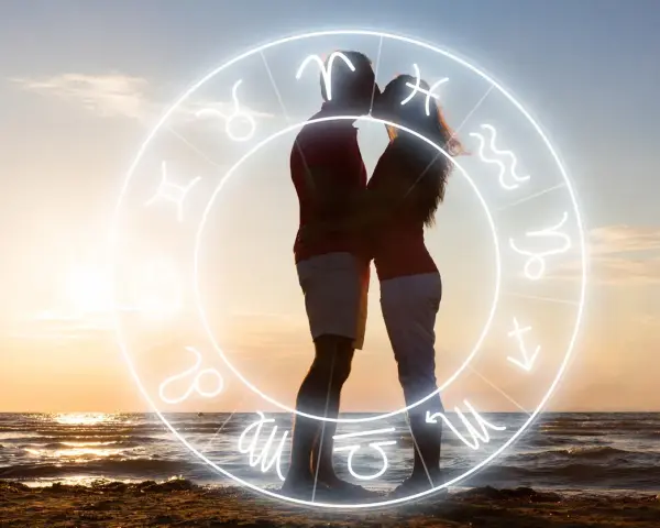 Para Skorpiona: para zakochanych na plaży w zachodzącym słońcu, otoczona znakiem zodiaku.
