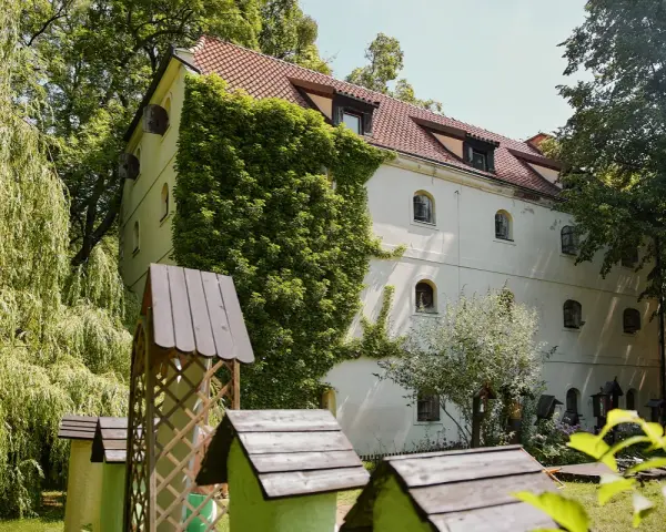 Oddział etnografii - spichlerz opacki, otoczony zielenią, z zabytkowymi ulami w ogrodzie.