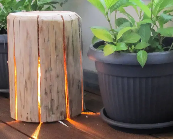 Un tronco di legno con fessure illuminate, un'idea creativa per come costruire una fioriera in legno.