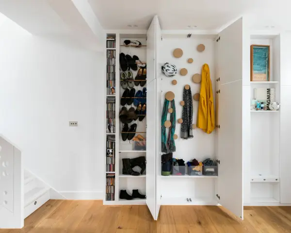 Moderne Garderobe Ideen: Offene Fächer mit Schuhen, Jacken und Schals. Ein Fahrradhelm hängt an der Wand.