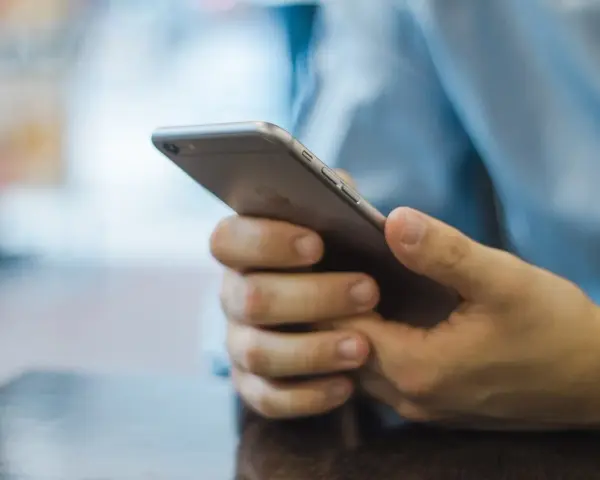 Dłonie trzymające smartfon, szukające inspiracji, jak zacząć rozmowę na Badoo.