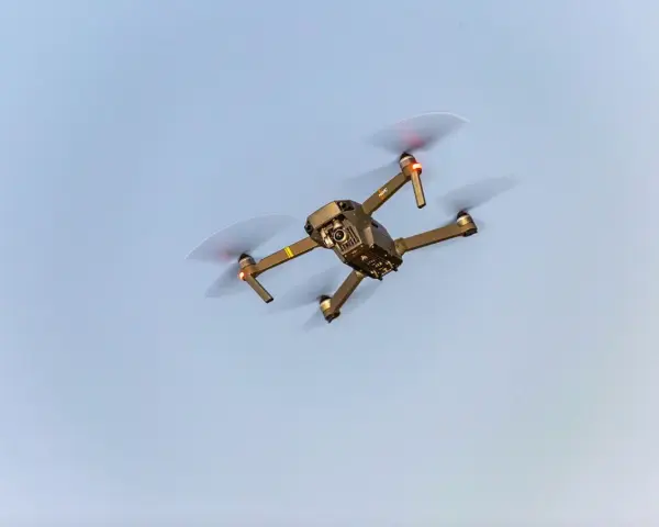 A drone flies in the sky, a reminder to check Maine drone laws before takeoff.