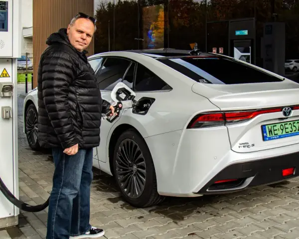 Mężczyzna tankuje białą Toyotę Mirai na jednej z pierwszych stacji wodorowych w Polsce.