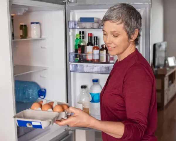 Frau holt Eier aus dem Kühlschrank. Nach einer Darmspiegelung ist leichte Kost wie Eier oft das erste Essen.