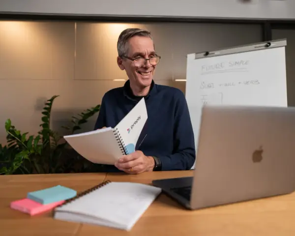 Lehrer erklärt auf Englisch "Future Simple", ein Adjektiv oder Adverb, mit einem Lächeln.
