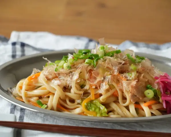 Udon z warzywami i szczypiorkiem, posypany płatkami katsuobushi. To właśnie katsuobushi co to jest, suszone płatki bonito, dodają daniu głębi smaku.