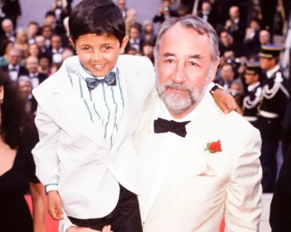 Un bambino sorridente, protagonista di "Nuovo Cinema Paradiso", abbracciato da un uomo con una rosa all'occhiello.