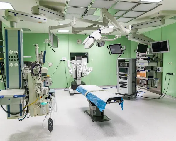 Nowoczesna sala operacyjna z robotem da Vinci, stołem zabiegowym i aparaturą medyczną.