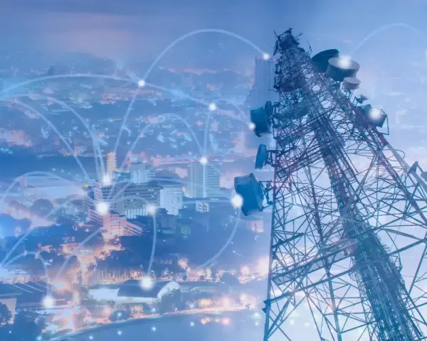 A telecommunications tower overlooks a city, with glowing lines connecting points, symbolizing network planning and optimization.
