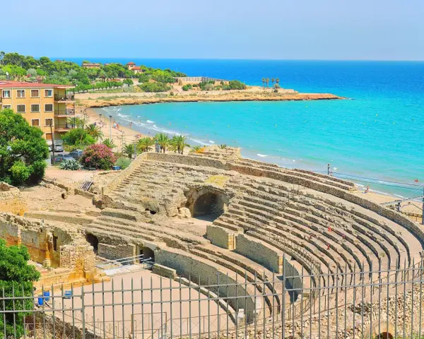 Ancient Roman amphitheater ruins overlooking a beautiful beach and turquoise sea. Discover Tarragona things to do, from history to relaxation.