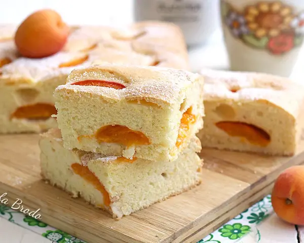 Fette di torta alle albicocche cremosa, soffice e profumata, con albicocche fresche e zucchero a velo.