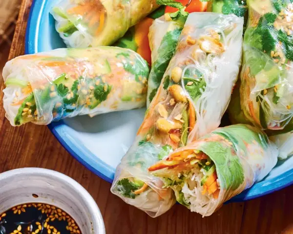Rouleaux de printemps frais et colorés, parfaits pour une recette facile. On y voit des vermicelles de riz, des légumes croquants et des cacahuètes.