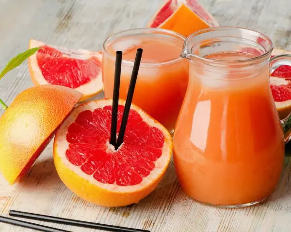 Orzeźwiający drink z grejpfrutem, podany w dzbanku i szklance, otoczony świeżymi owocami. Idealny na upalne dni.