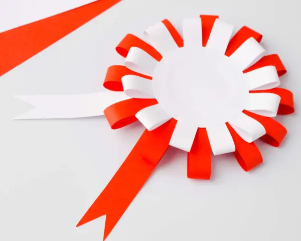 Papierowy kotylion w biało-czerwonych barwach, gotowy do ozdobienia. Idealny szablon do stworzenia patriotycznego akcentu.