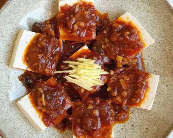 Tofu comida servida en un plato con salsa picante y jengibre rallado.