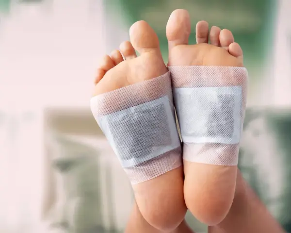 Close-up of feet with detox patches applied to the soles, demonstrating how to do a foot detox at home.