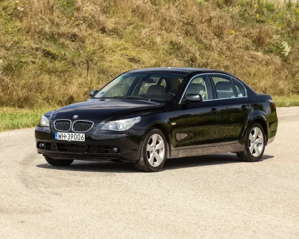 Czarne BMW 535d na tle zielonego wzgórza.