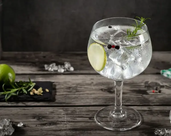 Orzeźwiający gin z tonikiem, udekorowany plasterkiem limonki, gałązką rozmarynu i ziarnami pieprzu. Idealny na letnie wieczory.