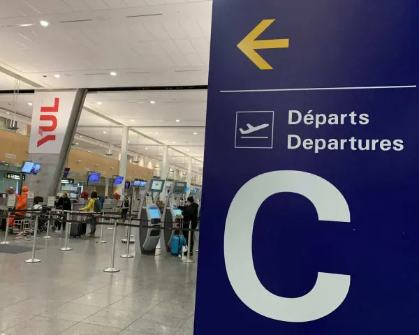 Tablica kierująca na lotnisku Montreal YUL, z napisem "Departures" i dużą literą "C".