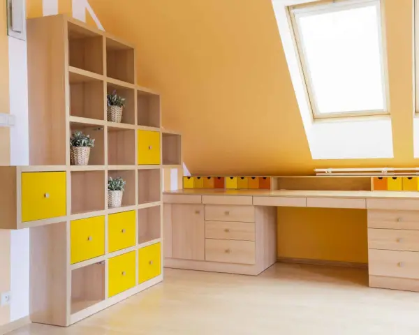 Luminosa mansarda con pareti arancioni e mobili in legno chiaro. Le idee colori pareti mansarda sono valorizzate da cubi contenitori gialli e un'ampia scrivania.