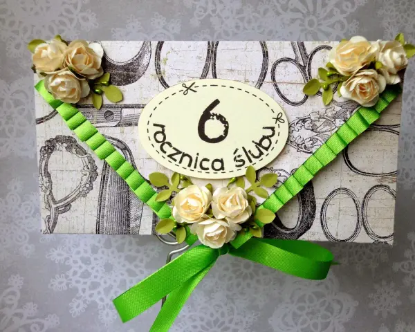 Elegancka kartka z ozdobami kwiatowymi i zieloną wstążką, z napisem "6 rocznica ślubu".