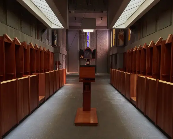 Rows of wooden stalls line the interior of a Carthusian monastery, leading towards an altar.