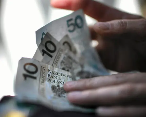 Dłonie trzymają polskie banknoty 10 i 50 zł. Czy na bierzmowanie daje się prezenty? Pieniądze mogą być odpowiedzią.