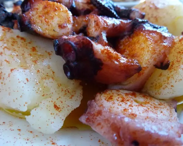 Pulpo con cachelos, un plato gallego tradicional. Tentáculos de pulpo cocidos y trozos de patata, todo espolvoreado con pimentón y aceite de oliva.