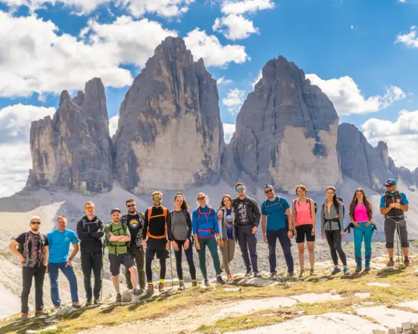 Grupa przyjaciół na tle Tre Cime di Lavaredo podczas niezapomnianego trekkingu w Dolomitach.