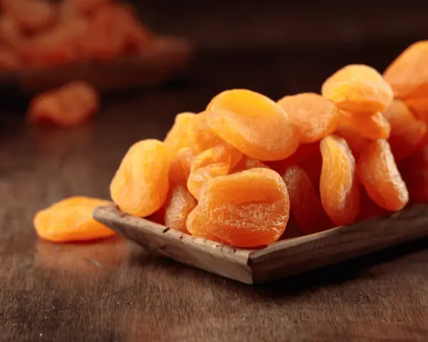 Getrocknete Aprikosen in einer Holzschale, ein gesunder Snack voller Vitamine.
