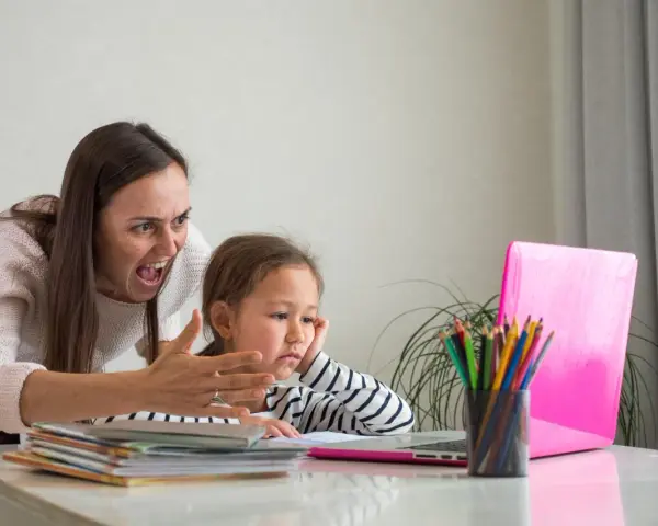 Zła kobieta krzyczy na dziecko przy laptopie.