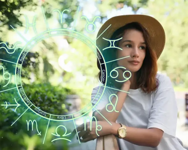 Kobieta w kapeluszu patrzy w dal, otoczona znakiem zodiaku. Wśród nich widać symbole Byka i Barana, sugerujące astrologiczne połączenie.