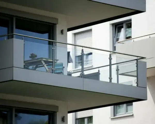 Nowoczesna loggia z przeszkloną balustradą, na której stoi stolik z kwiatami i krzesło.