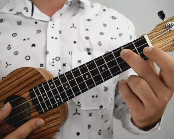 Dłoń dociska struny ukulele, tworząc akord. To jak czytanie tabulatury na gitarze, tylko na mniejszym instrumencie.