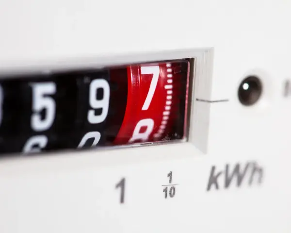 Zbliżenie na licznik przedpłatowy pokazujący 8597 kWh. Cyfry na obrotowych bębenkach, jeden z nich czerwony.