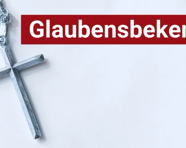 Ein silbernes Kreuz liegt neben dem Schriftzug "Glaubensbekenntnis".